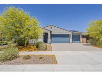 Charming single-story home featuring a blue garage door, desert landscaping, and a neutral color palette at 17704 W Fetlock Trl, Surprise, AZ 85387