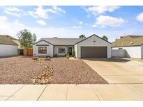 Inviting single-story home with desert landscaping, a gray roof, and a two-car garage at 19039 N 47Th Ave, Glendale, AZ 85308