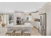 Bright kitchen featuring white cabinets, stainless appliances, granite counters and island with seating at 19039 N 47Th Ave, Glendale, AZ 85308