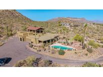 Expansive desert home features a sparkling pool, attached garage, and a unique architectural design amidst a stunning natural landscape at 8752 E Range Rider Trl, Mesa, AZ 85207