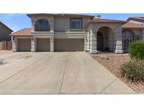 Charming home with a three car garage and a well-manicured lawn on a sunny day at 9548 W Keyser Dr, Peoria, AZ 85383