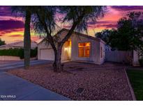Charming single-story home with desert landscaping, and a warm inviting glow from the large front window at 10735 W Bermuda Dr, Avondale, AZ 85392