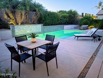 Inviting pool area featuring a dining table, lounge chair, and lush landscaping offering the perfect space for outdoor relaxation at 4628 W Whispering Wind Dr, Glendale, AZ 85310