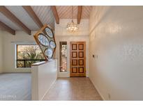 Inviting foyer with a wooden front door, unique art piece, and wood-beamed ceilings offering a warm welcome at 9008 N 83Rd St, Scottsdale, AZ 85258