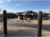 Desert home featuring stone accents, modern garage doors, and neutral colors blending with the natural landscape at 9750 E Troon North Dr, Scottsdale, AZ 85262