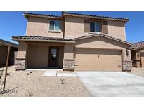 Inviting two-story home featuring a neutral color palette, a two-car garage, and a well-maintained gravel front yard at 1074 W West Virginia Ave, Florence, AZ 85132