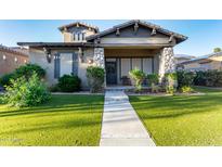 Charming single-story home featuring stone accents, a well-manicured lawn, and a welcoming front porch at 4565 N Point Ridge Rd, Buckeye, AZ 85396