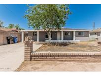 Charming single-story home featuring a brick wall, painted gray, and a mature tree shading the front at 5022 W Pierson St, Phoenix, AZ 85031