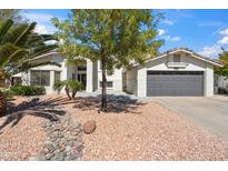 Charming single-story home boasting desert landscaping, a lush tree, and a gray garage door at 6164 E Greenway Ln, Scottsdale, AZ 85254