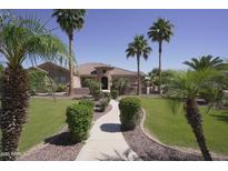 Charming single-story home featuring a manicured lawn, lush landscaping, and a stone-accented entrance at 16386 W Papago St, Goodyear, AZ 85338