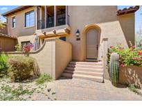 Inviting front entrance with a charming arched doorway, desert landscaping, and a private balcony above at 20704 N 90Th Pl # 1015, Scottsdale, AZ 85255