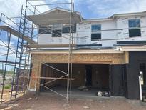 Unfinished two-story home with open garage door, scaffolding, and construction materials present at 5859 E Covey Ln, Phoenix, AZ 85054