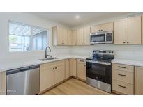 Bright kitchen featuring stainless steel appliances, light wood cabinets and white countertops at 6601 N 46Th Ln, Glendale, AZ 85301