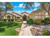 Charming single-story home featuring a lush green lawn and a stone walkway leading to the front door at 7734 E Monica Dr, Scottsdale, AZ 85255