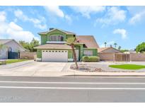 Charming two-story green home with a well-manicured front yard and white two-car garage at 8871 W Maryland Ave, Glendale, AZ 85305