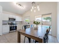 Eat-in kitchen features stainless steel appliances, white cabinetry, and a view of the pool at 11805 W Sunnyside Dr, El Mirage, AZ 85335