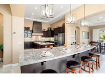 Open-concept kitchen featuring granite countertops, dark cabinetry, and bar seating at 12904 W Dale Ln, Peoria, AZ 85383