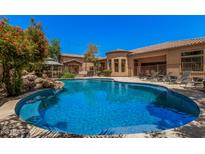 Inviting pool with a rock feature and lounge chairs, all set against a backdrop of manicured landscaping at 24348 S 201St Ct, Queen Creek, AZ 85142
