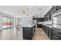 Bright, open kitchen with modern appliances, island with pendant lighting, and sliding doors to the patio at 31653 N 24Th Dr, Phoenix, AZ 85085
