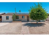 Charming single-story home featuring solar panels, desert landscaping, and a brick walkway at 3231 W Banff Ln, Phoenix, AZ 85053