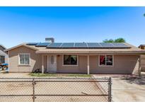Single-story home featuring solar panels, fenced front yard, neutral paint, and covered entry at 6814 W Berkeley Rd, Phoenix, AZ 85035