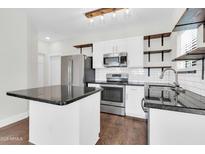 Bright kitchen featuring stainless steel appliances, a center island with granite countertop, and open wooden shelving at 1350 S Greenfield Rd # 1166, Mesa, AZ 85206