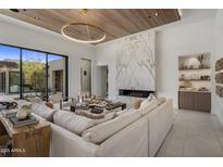 Bright living room featuring a fireplace with marble surround and wood plank ceiling with modern, round light fixture at 24863 N 103Rd Way, Scottsdale, AZ 85255