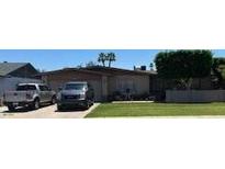 Well-maintained single-story home featuring a lush green lawn and a driveway with two parked vehicles at 2501 E Pebble Beach Dr, Tempe, AZ 85282