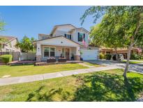 Inviting two-story home featuring a green lawn, charming front porch, and a lovely gray and white color scheme at 3931 E Weather Vane Rd, Gilbert, AZ 85296
