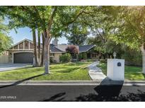 Charming single story home with mature trees, lush lawn, and unique stone and brick accents on a sunny day at 5112 N 41St St, Phoenix, AZ 85018