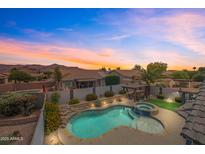 Sunset aerial view of a private pool with a spa, rock waterfall feature, and well-manicured landscaping at 8776 E Brilliant Sky Cir, Gold Canyon, AZ 85118