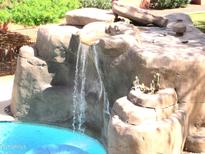 Landscaped pool area featuring an artificial rock waterfall and stone features at 12222 N Paradise Village S Pkwy # 325, Phoenix, AZ 85032