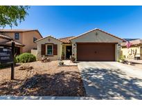 Charming single-story home features a well-manicured front yard, a two-car garage, and desert landscaping at 14112 W Larkspur Dr, Surprise, AZ 85379