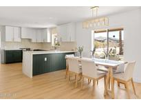 Bright kitchen features white cabinets with gold hardware, an island, and a dining area with a window view at 18428 N 42Nd St, Phoenix, AZ 85032