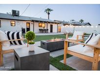Cozy backyard featuring a modern fire pit, outdoor seating, and a well-manicured lawn with string lights at 2023 N 79Th Pl, Scottsdale, AZ 85257