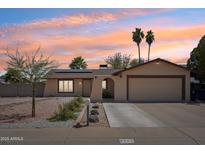 Charming single-story home featuring desert landscaping, a two-car garage, and solar panels for energy efficiency at 207 E Strahan Dr, Tempe, AZ 85283