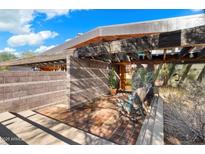 Open front porch with a brick floor, wood beams, potted cacti, and two chairs, creating an inviting entrance at 25232 N Horseshoe Trl, Scottsdale, AZ 85255
