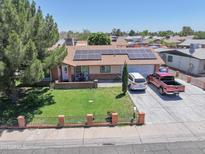Charming single-story home featuring solar panels, a well-manicured lawn, and a spacious driveway at 3107 N 79Th Ave, Phoenix, AZ 85033