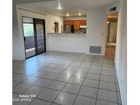 Open-concept living room featuring tile floors, sliding glass doors, and a breakfast bar overlooking the kitchen at 533 W Guadalupe Rd # 2126, Mesa, AZ 85210