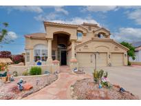 Inviting tan home featuring a three-car garage, arched entryway, and well manicured front yard landscaping at 5940 W Robinson Way, Chandler, AZ 85226