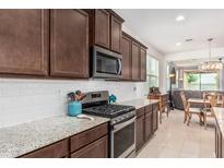 Modern kitchen with granite countertops, stainless steel appliances, and an open layout to the living area at 607 W Tenia Trl, San Tan Valley, AZ 85140