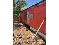 Shows the rundown exterior of a mobile home with peeling paint and boarded up windows in disrepair at 1416 E Southern Ave, Apache Junction, AZ 85119