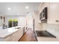 Bright kitchen features white cabinets, stainless steel appliances, stone countertops, and a gold faucet at 4525 N 66Th St # 95, Scottsdale, AZ 85251
