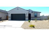 Inviting single-story home featuring a gray stucco facade, a two-car garage, and desert landscaping at 91 S Collier Ln, Casa Grande, AZ 85122