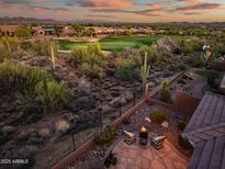 Inviting back patio with desert landscaping and golf course views, perfect for relaxing evenings by the fire pit at 41731 N Rolling Green Way, Anthem, AZ 85086