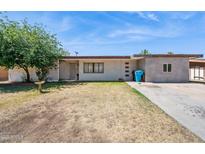 Charming single-story home with a minimalist front yard design, complemented by a mature tree at 5615 W Camelback Rd, Phoenix, AZ 85031