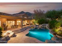 Stunning backyard with covered patio, outdoor seating, rock waterfall, and sparkling pool, perfect for entertaining at 5921 E Leisure Ln, Carefree, AZ 85377