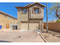 Two-story tan home featuring a two car garage and desert landscaping in front at 823 E Agua Fria Ln, Avondale, AZ 85323