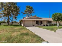 Inviting single-story home with a well-maintained lawn, mature trees, and a two-car garage at 10913 W Caron Dr, Sun City, AZ 85351