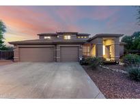Beautiful two-story home with a three car garage and well-maintained landscaping at dusk at 20432 N 87Th Dr, Peoria, AZ 85382